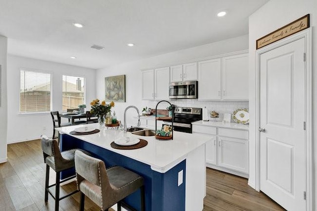 kitchen with a breakfast bar area, stainless steel appliances, white cabinets, and decorative backsplash