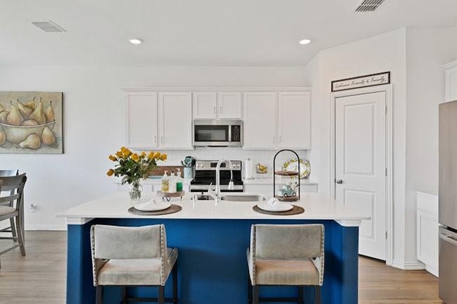 kitchen with white cabinets, stainless steel appliances, a kitchen breakfast bar, and a sink