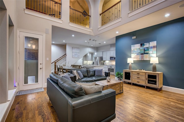 7401 Collin Mckinney Pkwy, Mckinney, TX 75070 - living room with light wood finished floors, a towering ceiling, stairway, baseboards, and recessed lighting