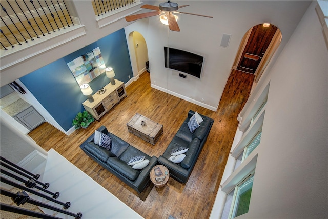 7401 Collin Mckinney Pkwy, Mckinney, TX 75070 - living area featuring arched walkways, wood finished floors, a ceiling fan, and a towering ceiling