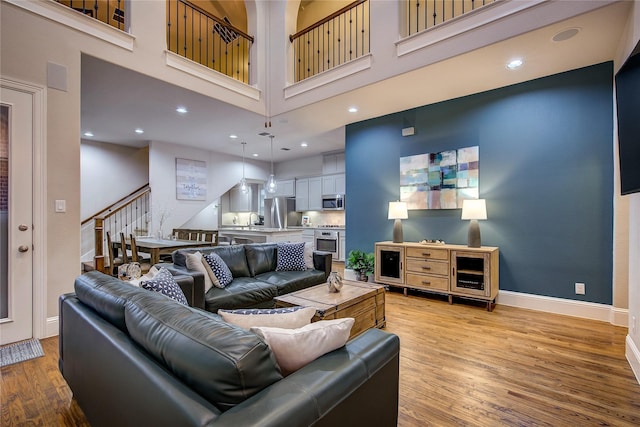 7401 Collin Mckinney Pkwy, Mckinney, TX 75070 - living room featuring a towering ceiling, light wood-type flooring, stairs, baseboards, and recessed lighting