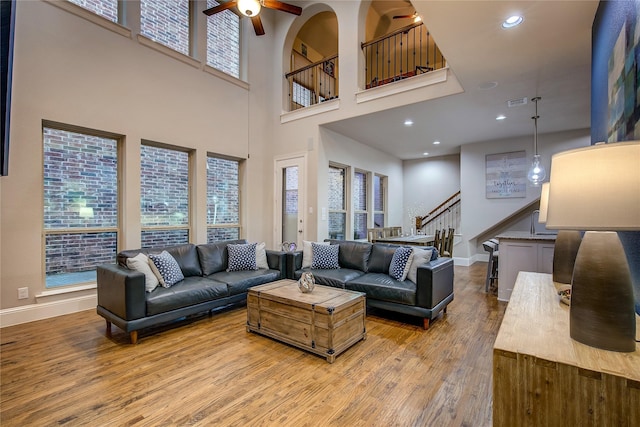 7401 Collin Mckinney Pkwy, Mckinney, TX 75070 - living area with light wood-style floors, stairs, ceiling fan, baseboards, and a towering ceiling
