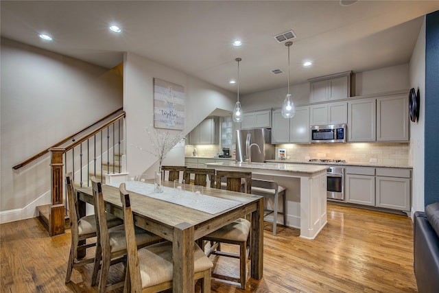 7401 Collin Mckinney Pkwy, Mckinney, TX 75070 - kitchen with appliances with stainless steel finishes, backsplash, light wood-type flooring, recessed lighting, and an island with sink