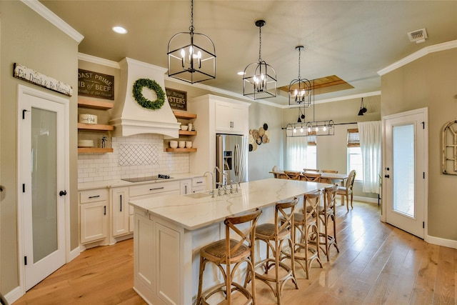 kitchen with open shelves, a sink, stainless steel fridge with ice dispenser, white cabinetry, and visible vents