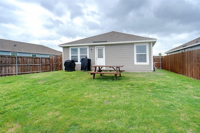 rear view of property with a fenced backyard and a lawn