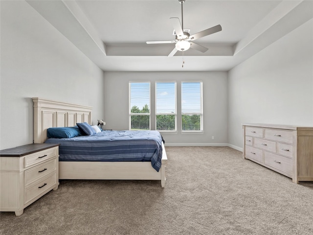 carpeted bedroom featuring a raised ceiling and ceiling fan