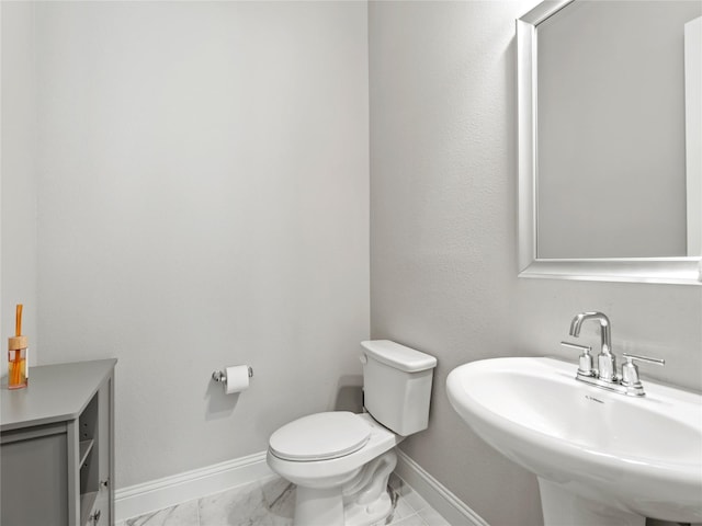 bathroom featuring baseboards, a sink, marble finish floor, and toilet