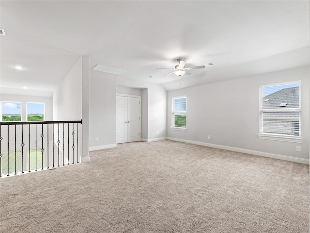 empty room with carpet floors, baseboards, a ceiling fan, and visible vents