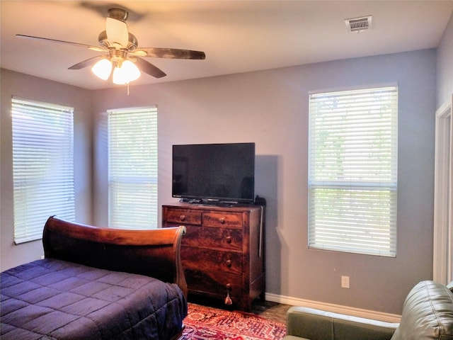 bedroom featuring baseboards, visible vents, multiple windows, and ceiling fan