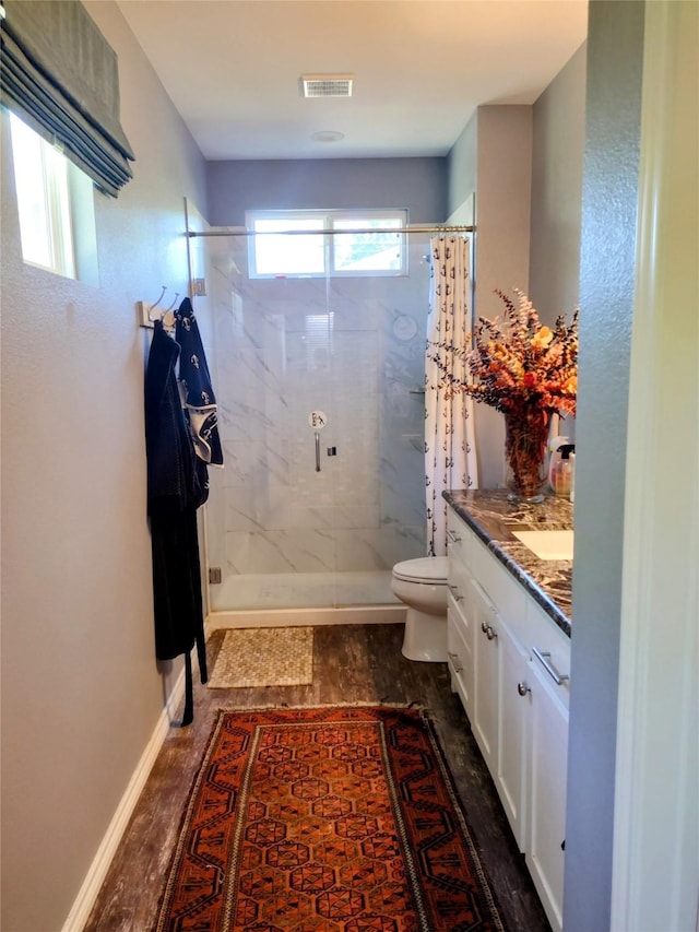 full bathroom featuring vanity, toilet, wood finished floors, visible vents, and a stall shower