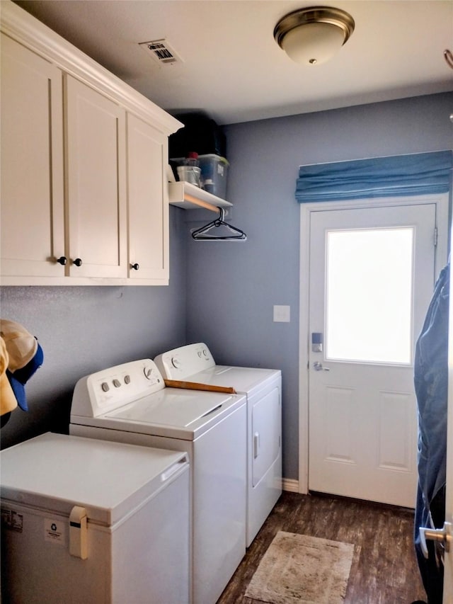 washroom with visible vents, cabinet space, dark wood-type flooring, and washing machine and dryer