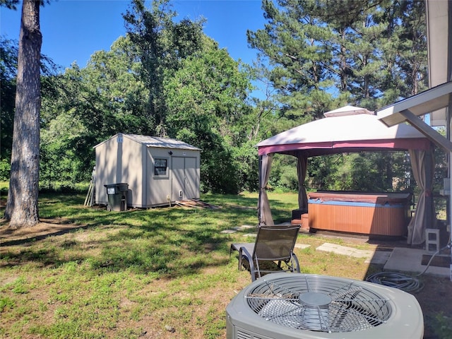view of yard featuring a gazebo, a hot tub, a storage shed, central air condition unit, and an outdoor structure
