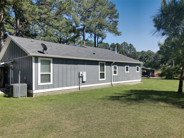 back of property with a lawn, central AC unit, and board and batten siding