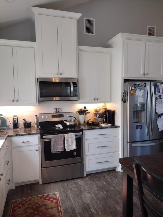 kitchen featuring dark stone counters, appliances with stainless steel finishes, white cabinets, and visible vents