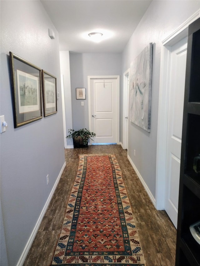 corridor featuring baseboards and wood finished floors