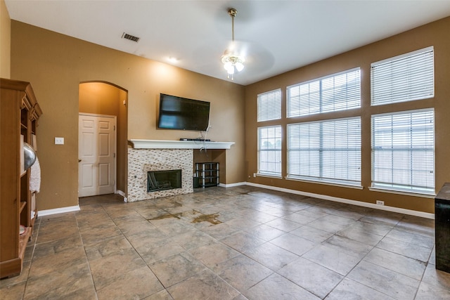 4619 Forest Park Rd, Plano, TX 75024 - unfurnished living room featuring a tile fireplace, arched walkways, ceiling fan, and baseboards
