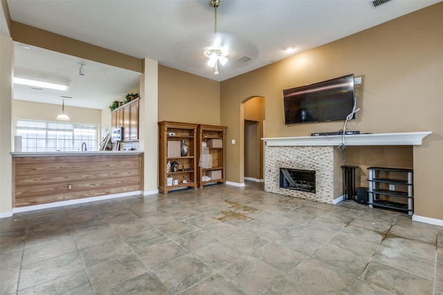 4619 Forest Park Rd, Plano, TX 75024 - unfurnished living room with arched walkways, a tiled fireplace, baseboards, a ceiling fan, and stone finish flooring