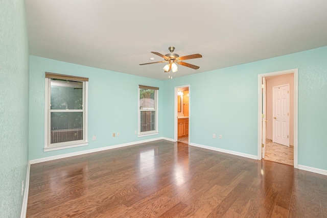 unfurnished room with baseboards, ceiling fan, and dark wood-style flooring