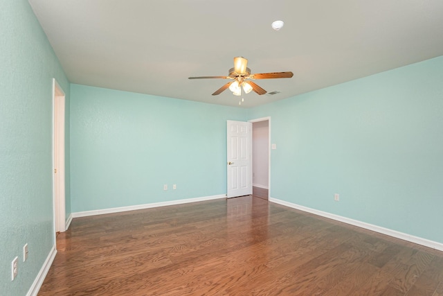 empty room with a ceiling fan, baseboards, visible vents, and wood finished floors
