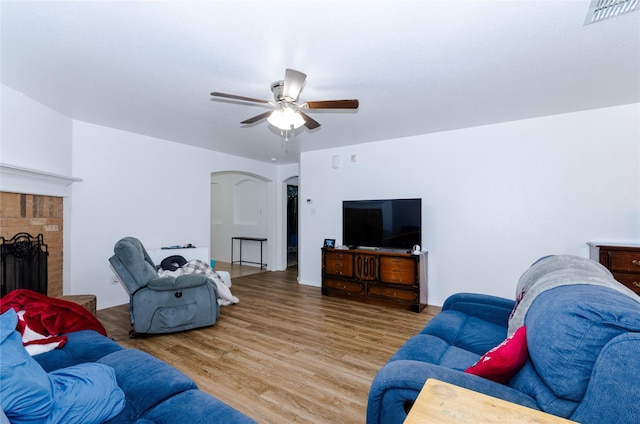 105 Fossil Way, Alvarado, TX 76009 - living area with wood finished floors, a ceiling fan, a fireplace, and arched walkways