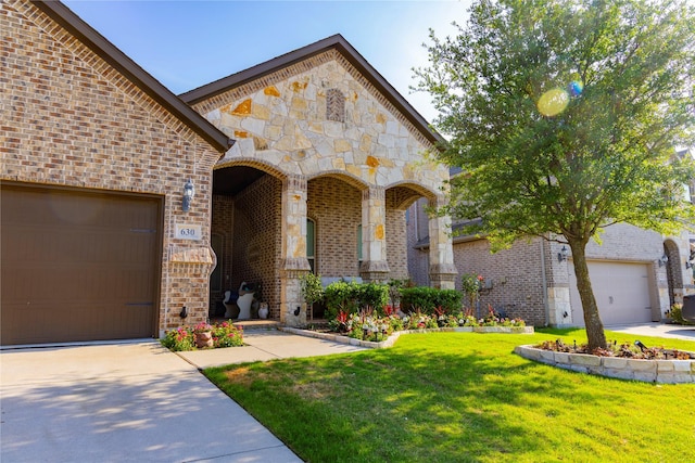 view of front of house with a front lawn, stone siding, a garage, brick siding, and driveway