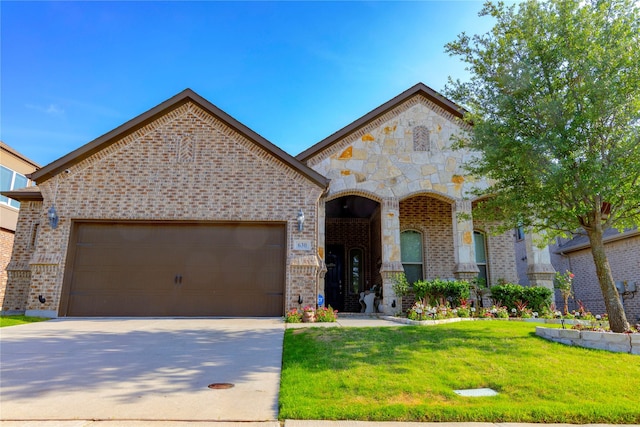 french country inspired facade featuring a front yard, brick siding, concrete driveway, an attached garage, and stone siding