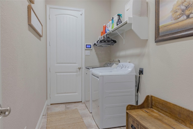 laundry area featuring independent washer and dryer, light tile patterned flooring, laundry area, and baseboards