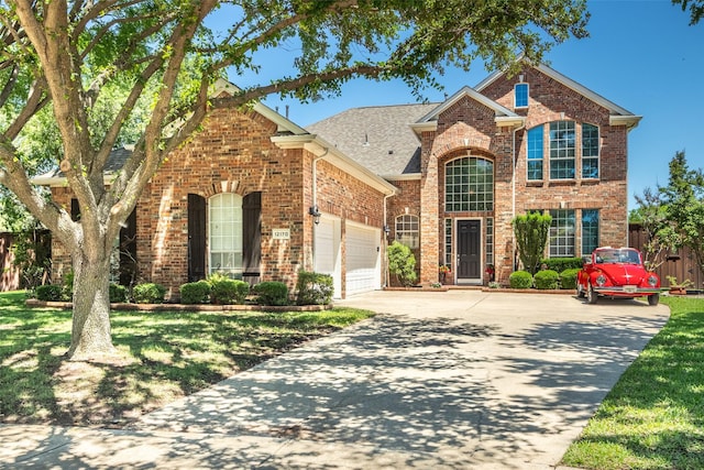 traditional-style home with an attached garage, fence, a front yard, brick siding, and driveway