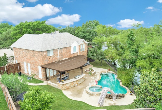 rear view of house with a patio, a pool with connected hot tub, a lawn, a fenced backyard, and brick siding
