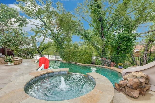 view of swimming pool featuring a patio area, a pool with connected hot tub, a water slide, and a fenced backyard