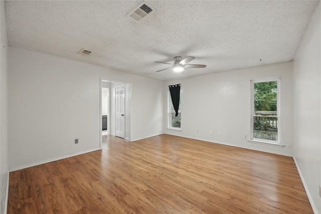 empty room featuring a ceiling fan, a textured ceiling, visible vents, and light wood-type flooring