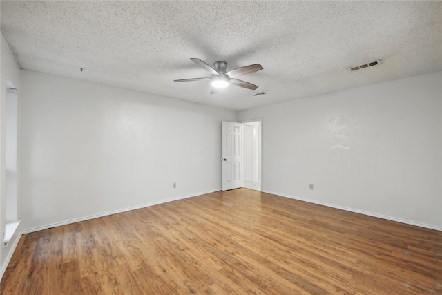unfurnished room with light wood-style floors, a ceiling fan, a textured ceiling, and visible vents