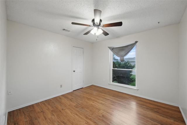 spare room featuring baseboards, a ceiling fan, wood finished floors, and visible vents