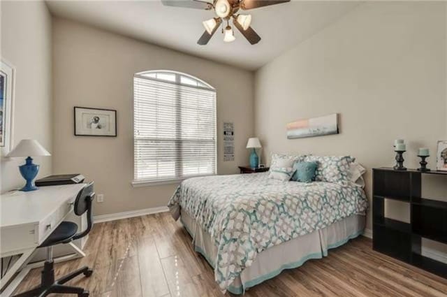 bedroom featuring a ceiling fan, baseboards, and wood finished floors