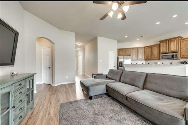 living area with ceiling fan, arched walkways, light wood-type flooring, baseboards, and recessed lighting
