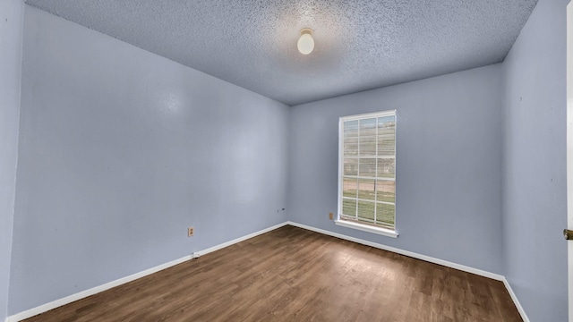 unfurnished room featuring a textured ceiling, dark wood finished floors, and baseboards