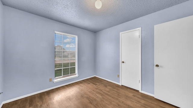 spare room with baseboards, a textured ceiling, and wood finished floors