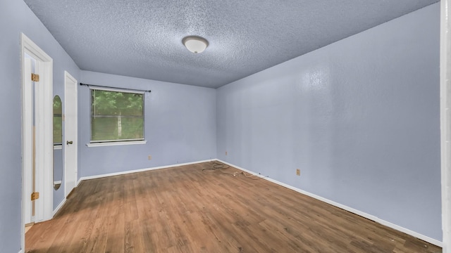 spare room featuring baseboards, a textured ceiling, and wood finished floors