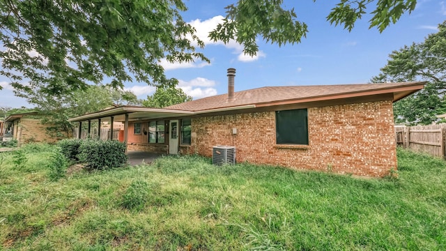 back of property featuring fence, cooling unit, and brick siding