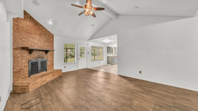 unfurnished living room with a ceiling fan, wood finished floors, a fireplace, and beamed ceiling