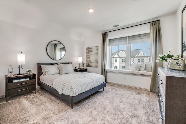 bedroom with baseboards, visible vents, vaulted ceiling, and light colored carpet