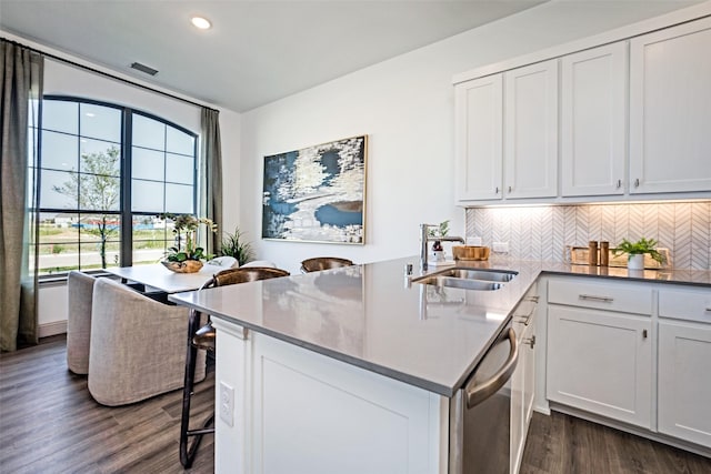 kitchen with decorative backsplash, visible vents, dishwasher, a sink, and dark wood-style floors