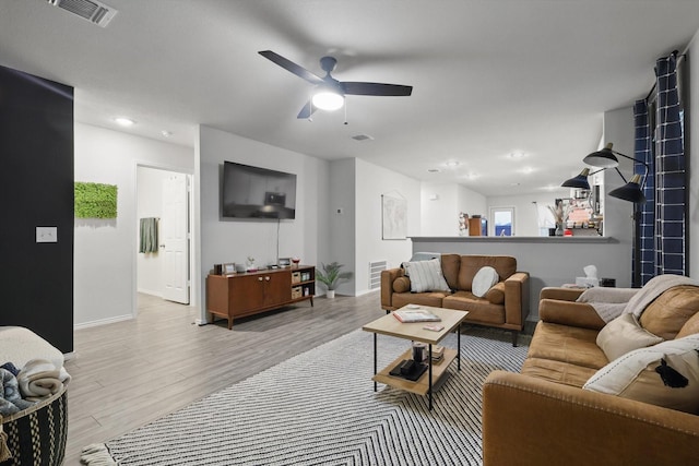 living room with ceiling fan, visible vents, and wood finished floors