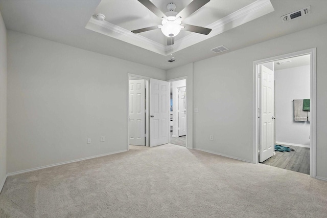 unfurnished bedroom with visible vents, a raised ceiling, and crown molding
