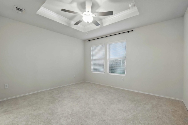 carpeted empty room featuring baseboards, ornamental molding, a ceiling fan, and a tray ceiling