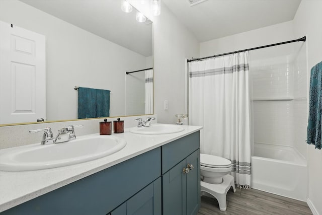 full bath featuring double vanity, a sink, wood finished floors, and toilet