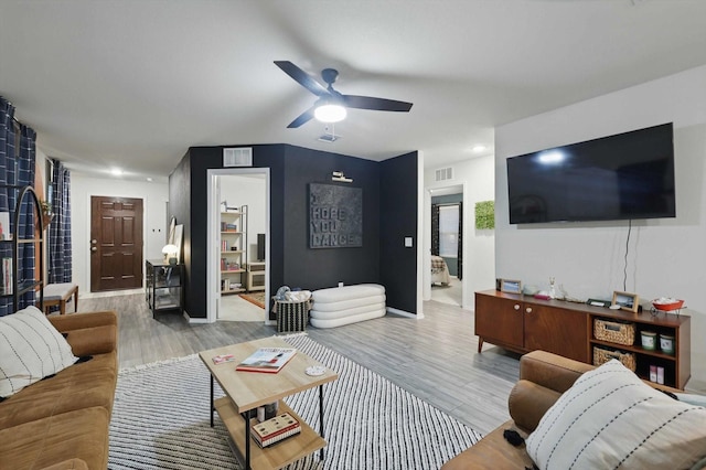 living area with a ceiling fan, visible vents, and wood finished floors