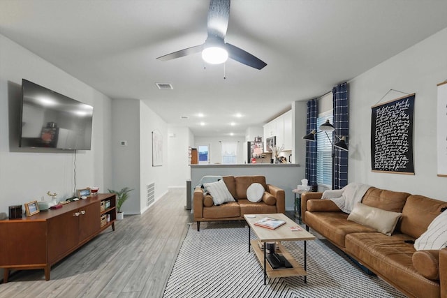 living area with a ceiling fan, baseboards, visible vents, and light wood-type flooring