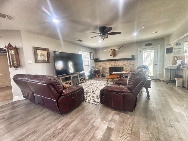 living room with wood finished floors, ceiling fan, a fireplace, and healthy amount of natural light