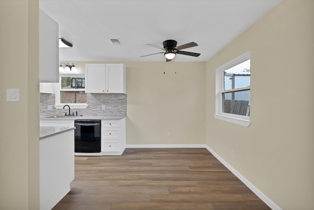 kitchen featuring ceiling fan, tasteful backsplash, a sink, white cabinets, and black dishwasher